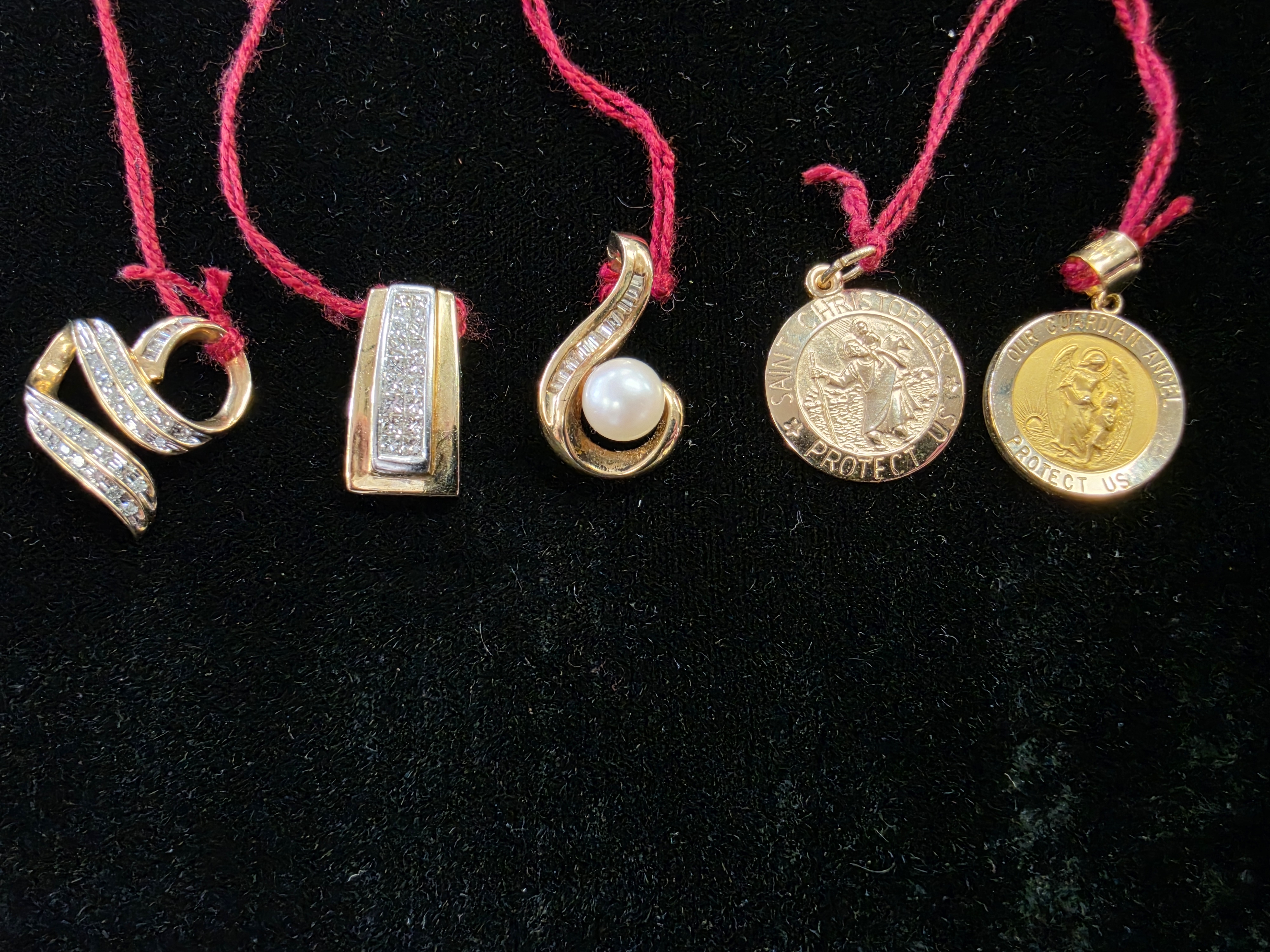 Gold and diamond pendants including infinity, pearl, and religious designs