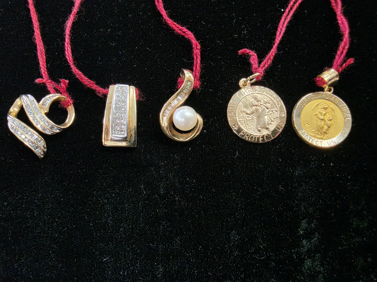 Gold and diamond pendants including infinity, pearl, and religious designs