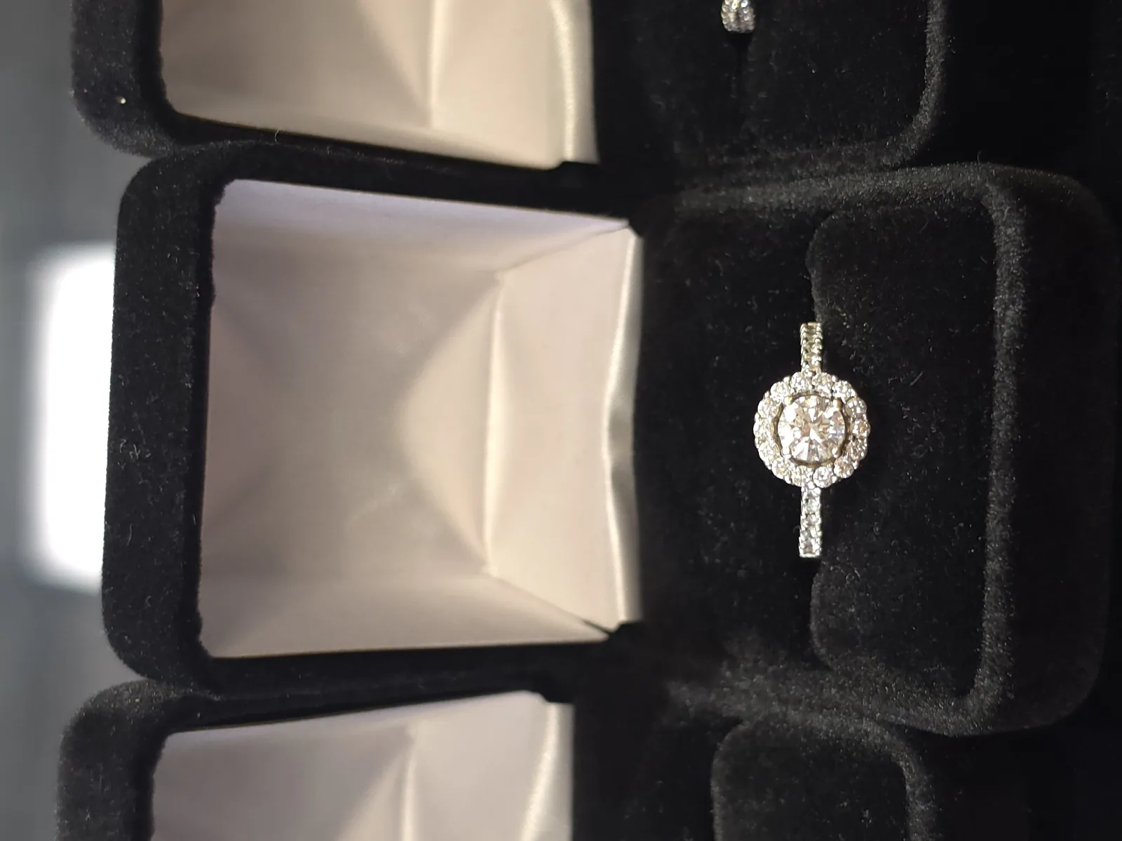 Diamond engagement ring with halo setting in display case